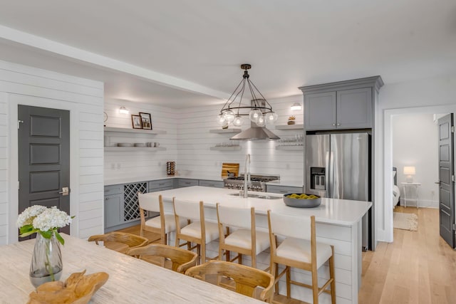 kitchen featuring a breakfast bar, open shelves, light countertops, gray cabinetry, and light wood-style floors