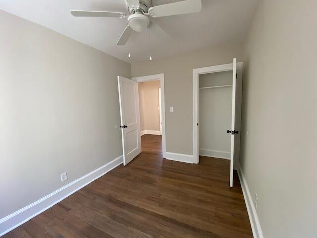 unfurnished bedroom with dark wood-type flooring, ceiling fan, and a closet