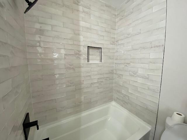 bathroom with tiled shower / bath and toilet