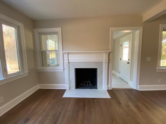 unfurnished living room with dark hardwood / wood-style floors, a premium fireplace, and a wealth of natural light