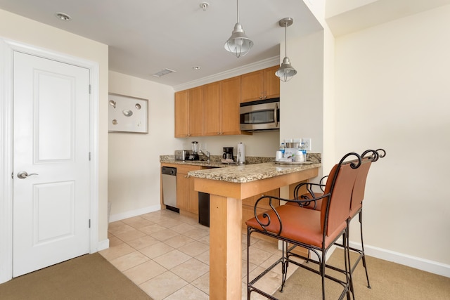 kitchen with light tile patterned floors, appliances with stainless steel finishes, a breakfast bar, hanging light fixtures, and light countertops