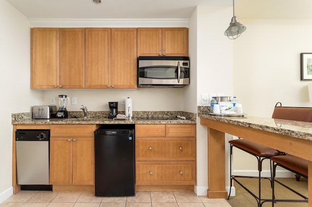 kitchen with light stone countertops, light tile patterned floors, stainless steel microwave, and brown cabinetry