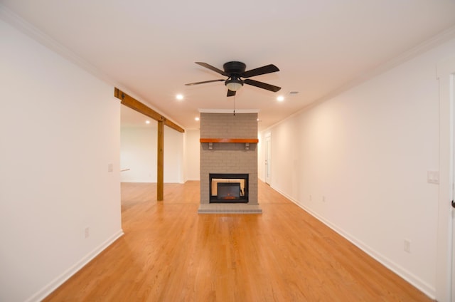 unfurnished living room with ornamental molding, a brick fireplace, ceiling fan, and light wood-type flooring