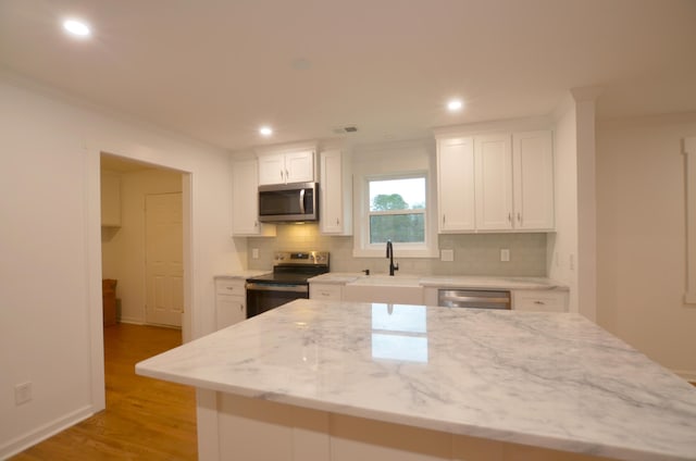 kitchen with stainless steel appliances, crown molding, white cabinets, and decorative backsplash