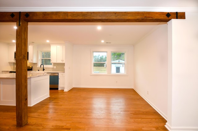 unfurnished living room featuring crown molding, sink, and light hardwood / wood-style flooring