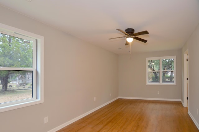 empty room featuring ceiling fan, light wood-type flooring, and a wealth of natural light