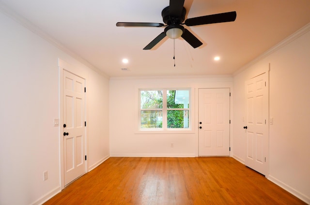 foyer entrance with wood-type flooring, ceiling fan, and crown molding