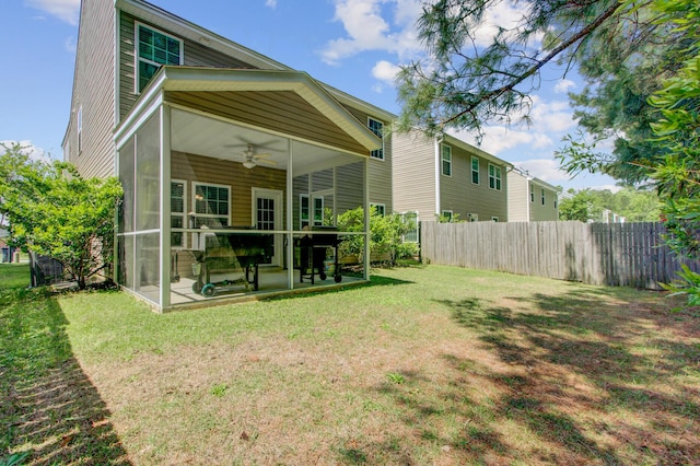 rear view of house with a sunroom, a yard, a ceiling fan, a patio area, and fence