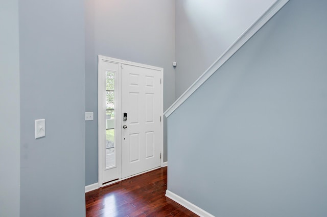 entrance foyer featuring dark wood-type flooring, a towering ceiling, and baseboards