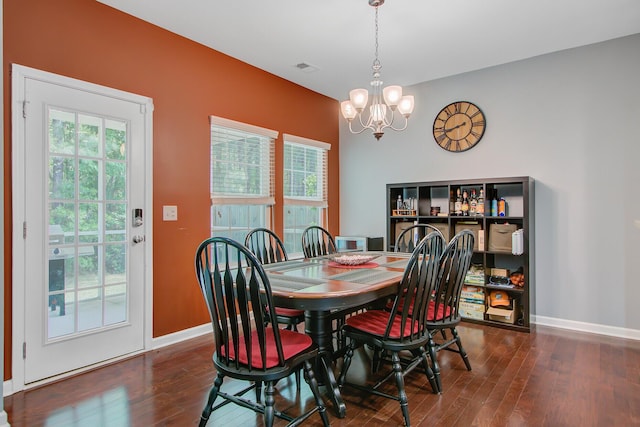dining room with dark wood-type flooring, a notable chandelier, baseboards, and visible vents