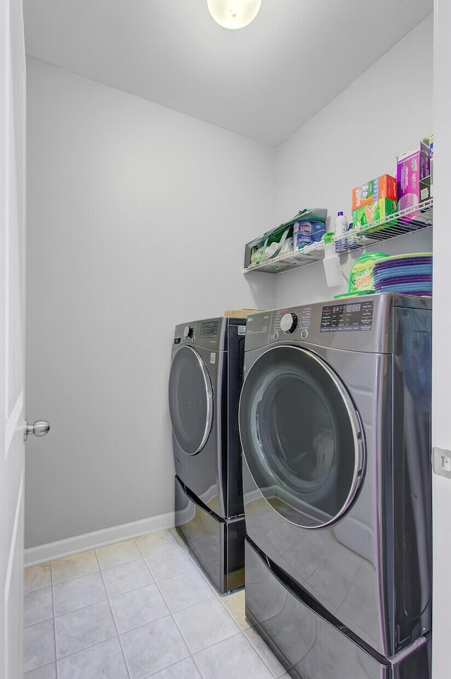 washroom featuring laundry area, baseboards, tile patterned flooring, and washer and clothes dryer