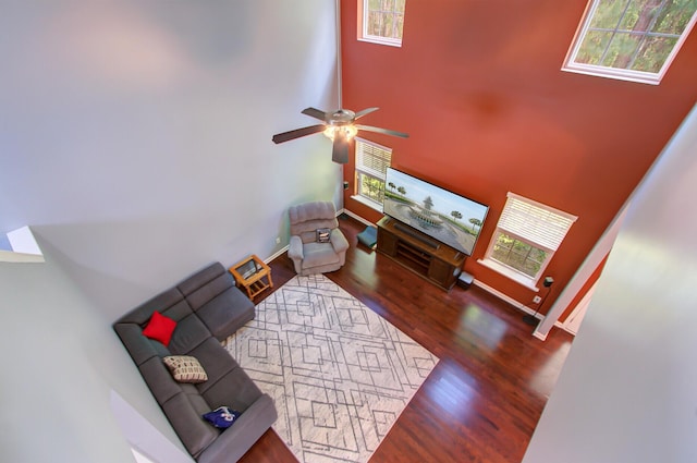 living room with a high ceiling, a healthy amount of sunlight, wood finished floors, and ceiling fan