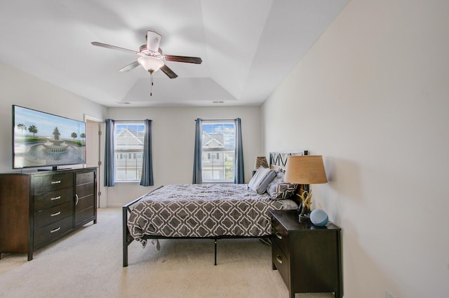bedroom featuring a tray ceiling, light colored carpet, and a ceiling fan