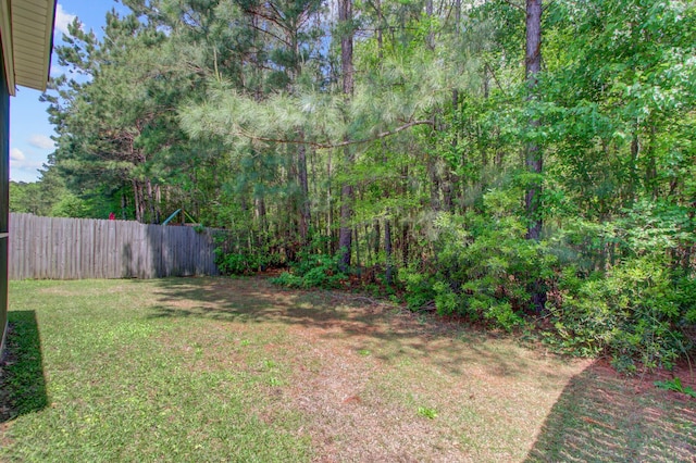 view of yard featuring a wooded view and fence