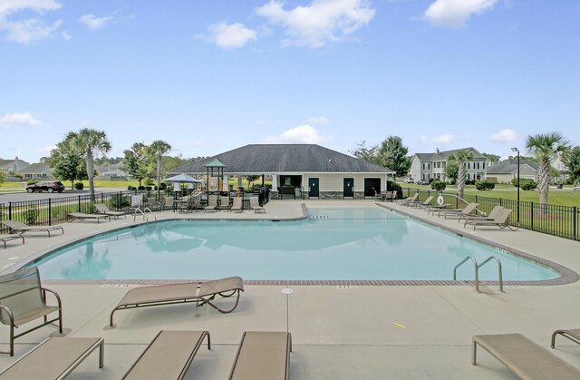 community pool with a patio area and fence