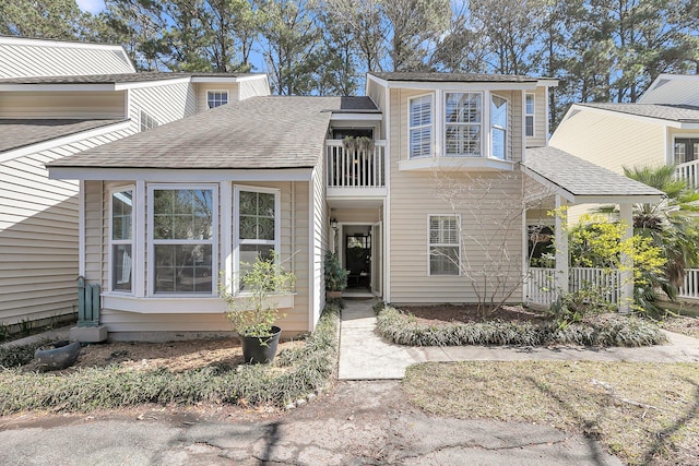 view of front of home with a balcony and roof with shingles