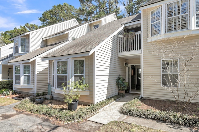 view of side of home with a balcony and roof with shingles