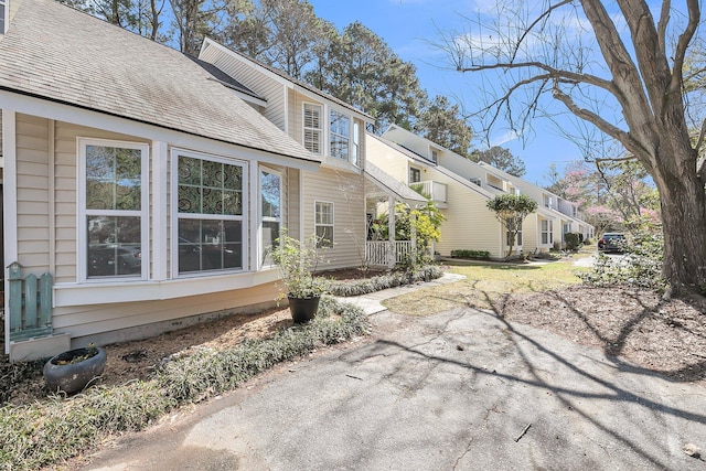 view of side of property with a residential view and a shingled roof