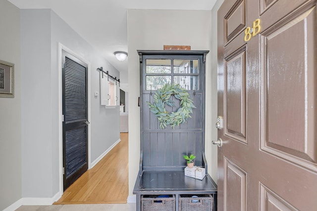 entryway with baseboards, a barn door, and wood finished floors