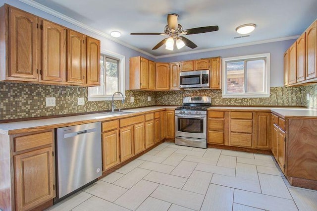 kitchen with sink, crown molding, ceiling fan, stainless steel appliances, and decorative backsplash