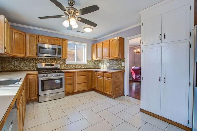 kitchen with decorative backsplash, ornamental molding, stainless steel appliances, and ceiling fan with notable chandelier