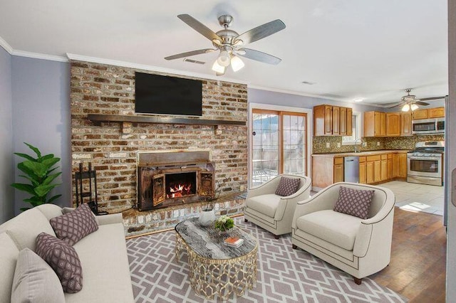 living room with crown molding, ceiling fan, a fireplace, and sink