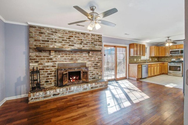 unfurnished living room with crown molding, a brick fireplace, ceiling fan, and light wood-type flooring