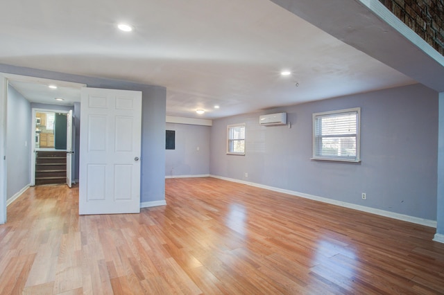 unfurnished room featuring plenty of natural light, a wall mounted air conditioner, and light hardwood / wood-style floors