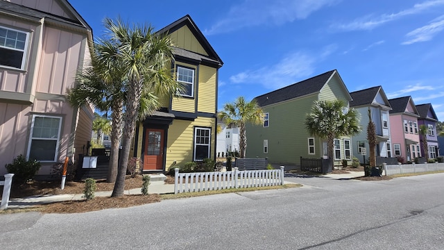 townhome / multi-family property with a fenced front yard, a residential view, and board and batten siding