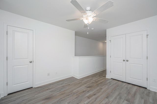 interior space featuring a closet, wood finished floors, a ceiling fan, and baseboards