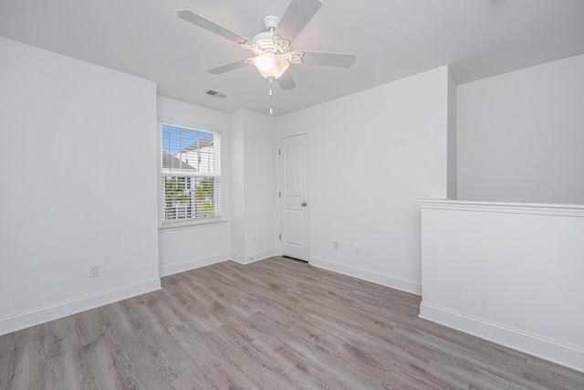 spare room featuring a ceiling fan, wood finished floors, visible vents, and baseboards