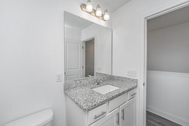 bathroom featuring wood finished floors, vanity, toilet, and baseboards