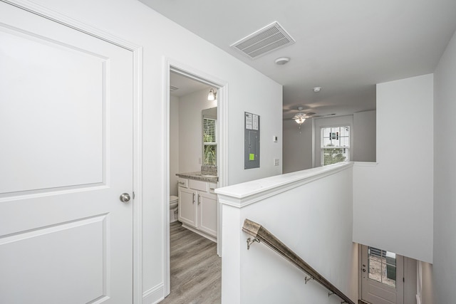 hallway featuring light wood finished floors, visible vents, and an upstairs landing