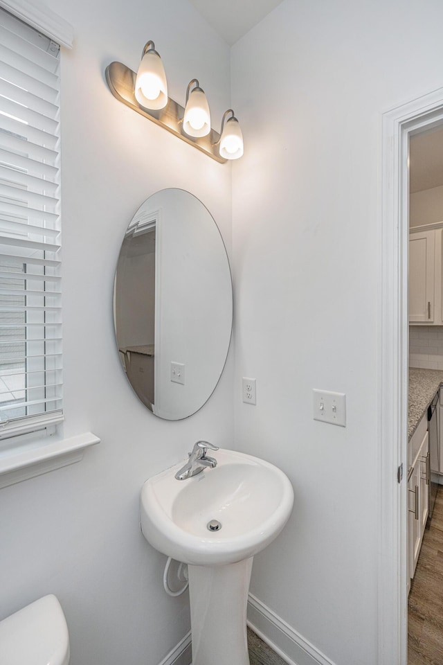 half bathroom featuring baseboards, toilet, and wood finished floors