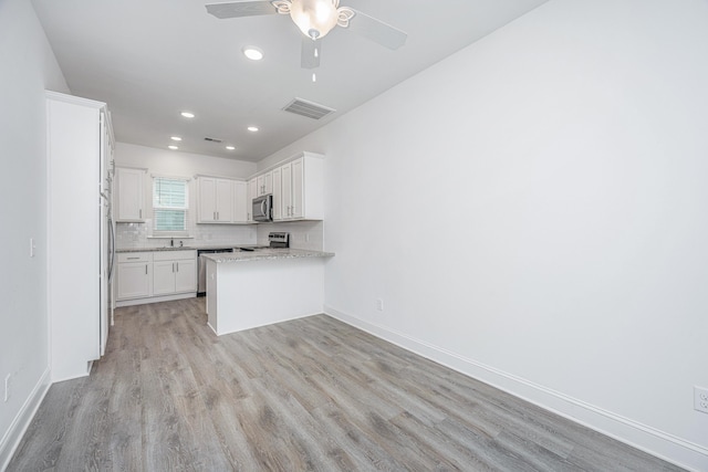 kitchen with light wood finished floors, baseboards, visible vents, appliances with stainless steel finishes, and backsplash