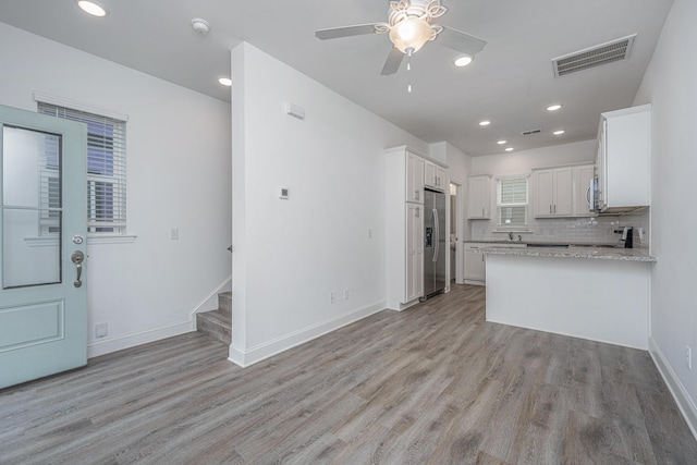 kitchen with stainless steel appliances, visible vents, backsplash, light wood-style floors, and white cabinets