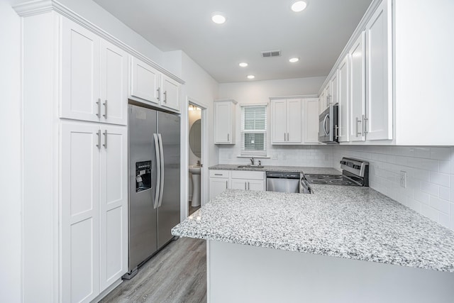 kitchen with light wood finished floors, visible vents, decorative backsplash, appliances with stainless steel finishes, and white cabinetry