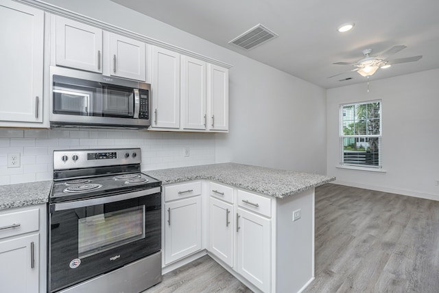 kitchen featuring light wood finished floors, visible vents, decorative backsplash, a peninsula, and stainless steel appliances