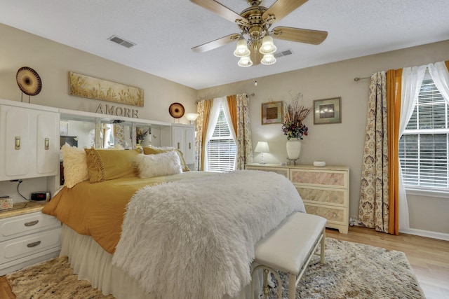 bedroom featuring ceiling fan, a textured ceiling, and light hardwood / wood-style flooring