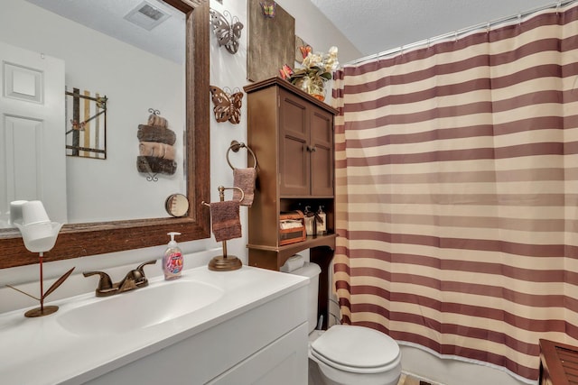 bathroom with a shower with curtain, a textured ceiling, vanity, and toilet