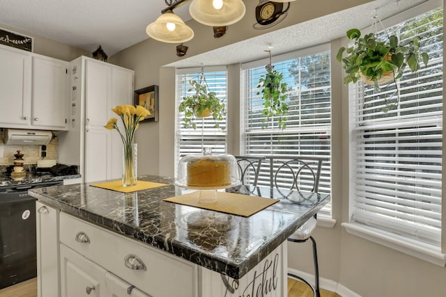 kitchen featuring dark stone countertops, white cabinets, pendant lighting, and a center island