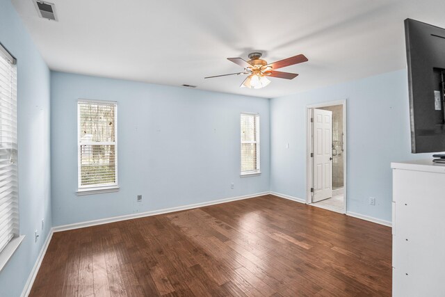 empty room featuring wood-type flooring, visible vents, ceiling fan, and baseboards