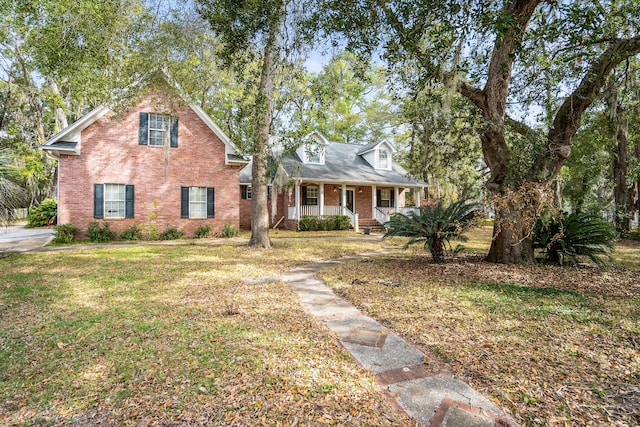 view of front facade featuring a front yard, covered porch, and brick siding