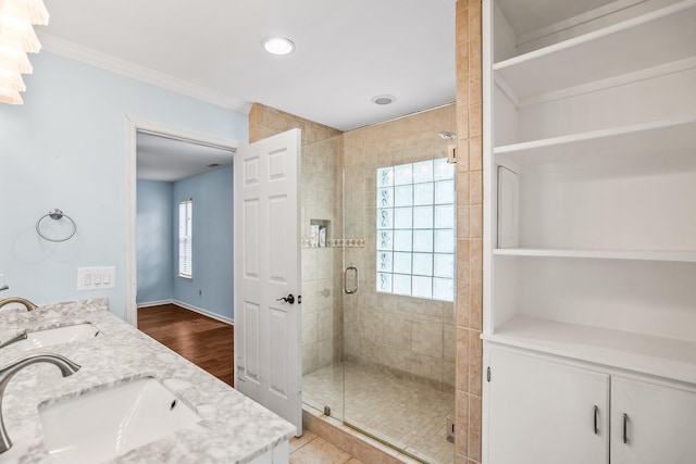 full bath with double vanity, a shower stall, baseboards, and a sink