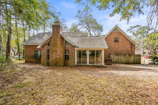 back of house with crawl space, roof with shingles, a chimney, and brick siding