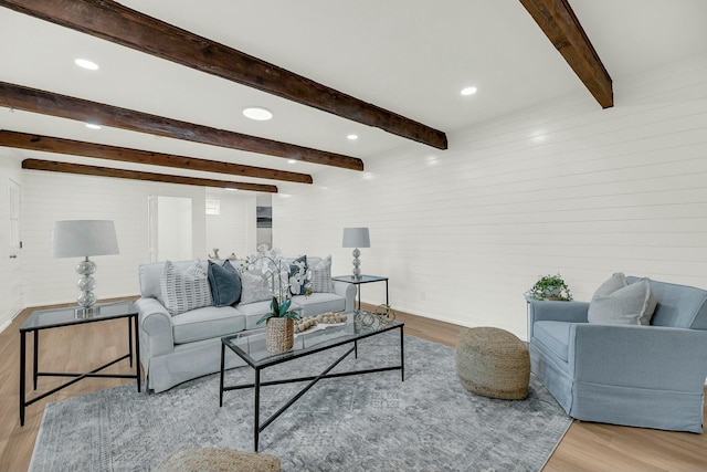 living room with beam ceiling, wooden walls, and light hardwood / wood-style floors