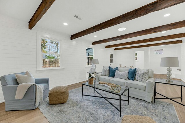 living room featuring wooden walls, light hardwood / wood-style flooring, and beamed ceiling