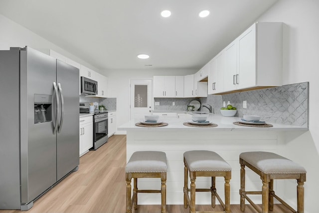 kitchen featuring white cabinetry, kitchen peninsula, and appliances with stainless steel finishes