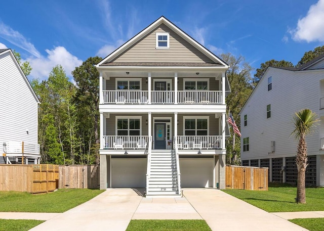 beach home with covered porch, stairway, a balcony, a garage, and driveway