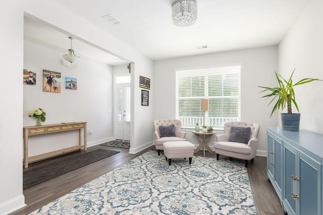 living area with dark wood-style flooring, visible vents, and a wealth of natural light
